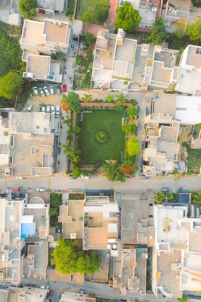 Services Aerial view of a residential district in India showcasing modern architecture and a central green park.